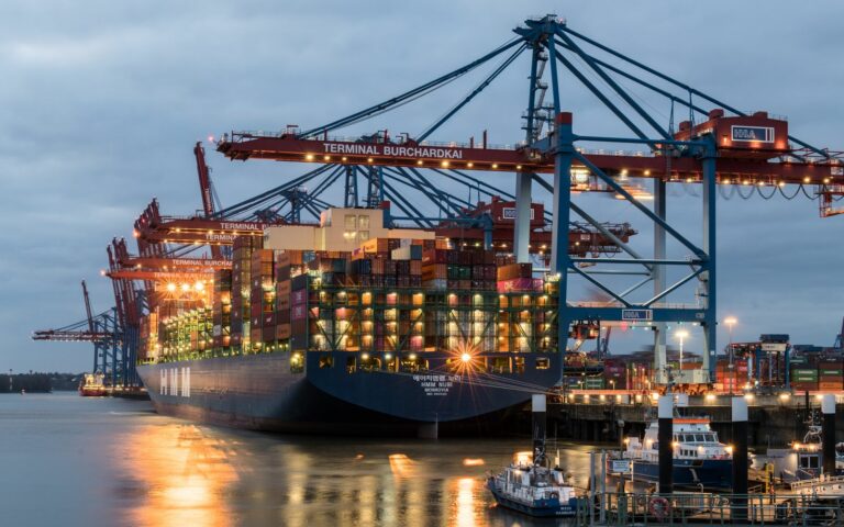 Container ship being loaded at a deep-water terminal, the point where import currency exposure begins