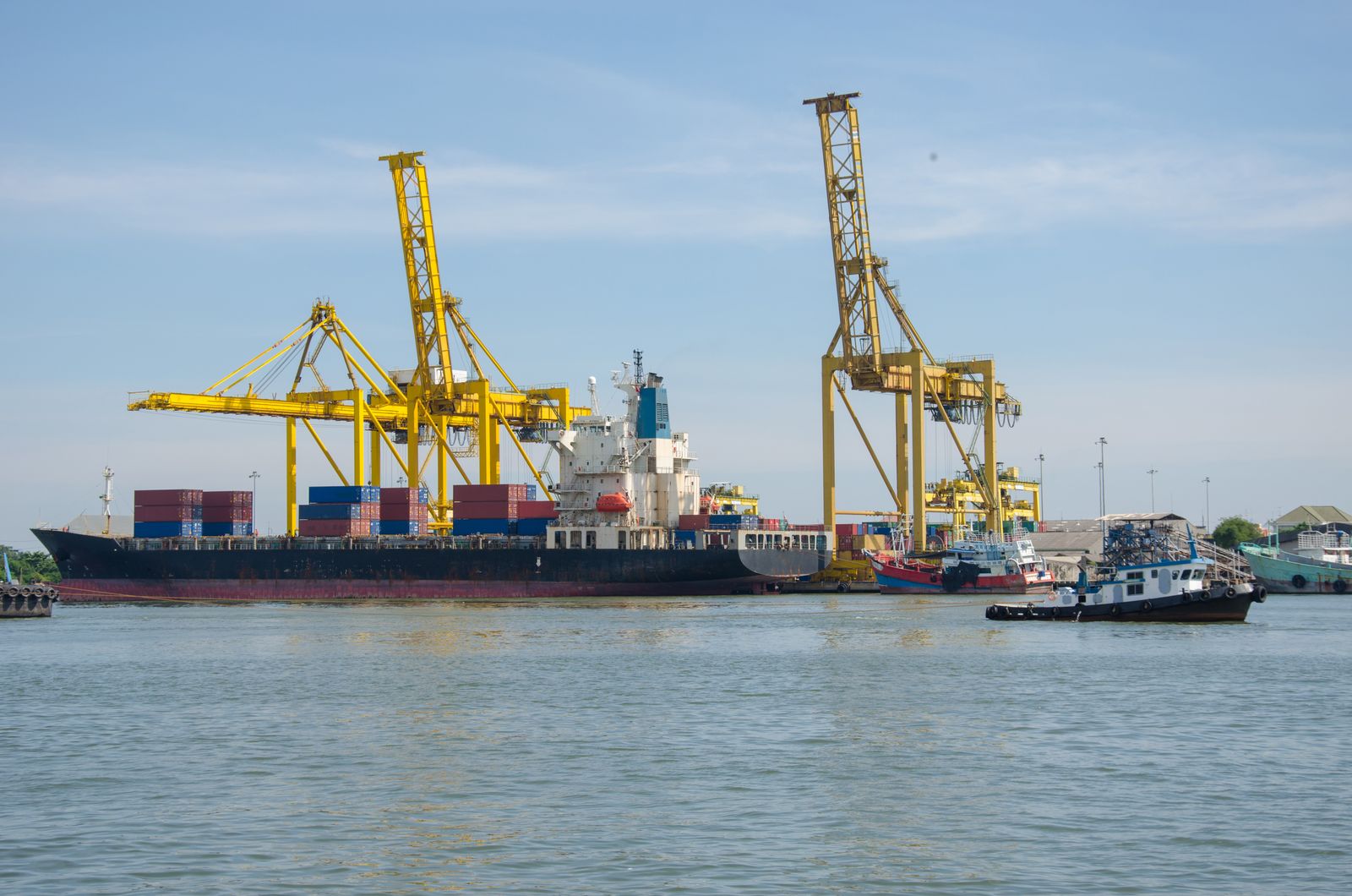Cargo ship docked at an industrial container port with cranes, illustrating Asia to West Africa shipping routes