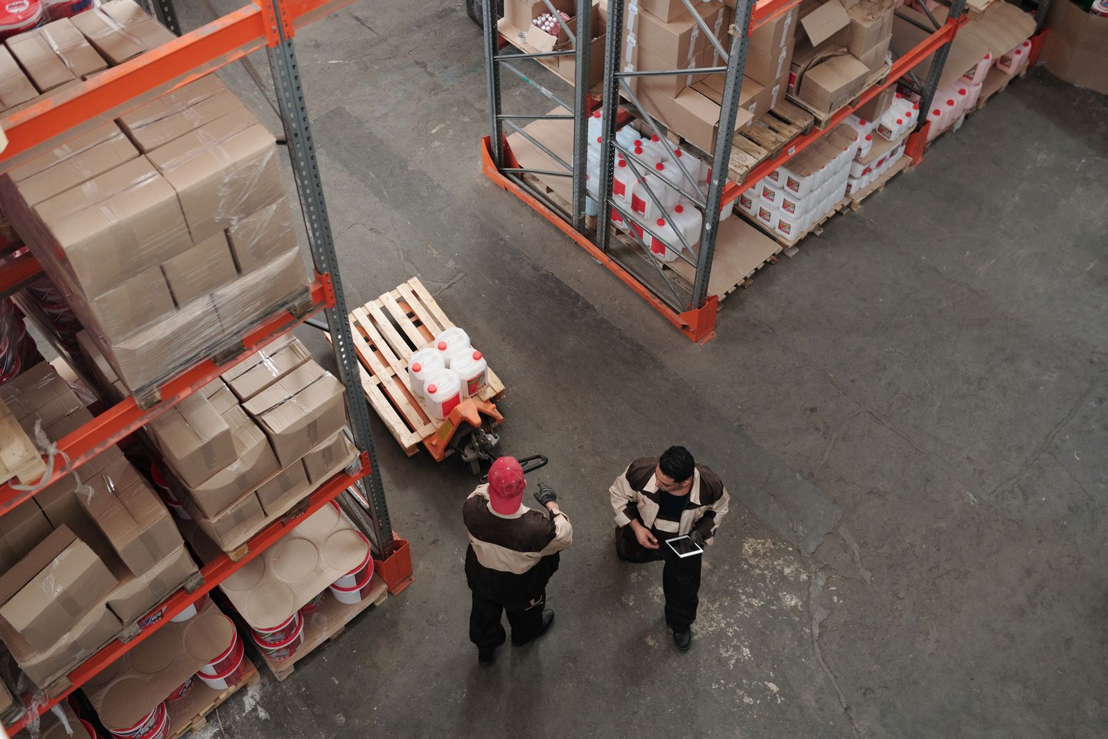 Entrepot vu de haut, palettes et magasiniers organisant les stocks