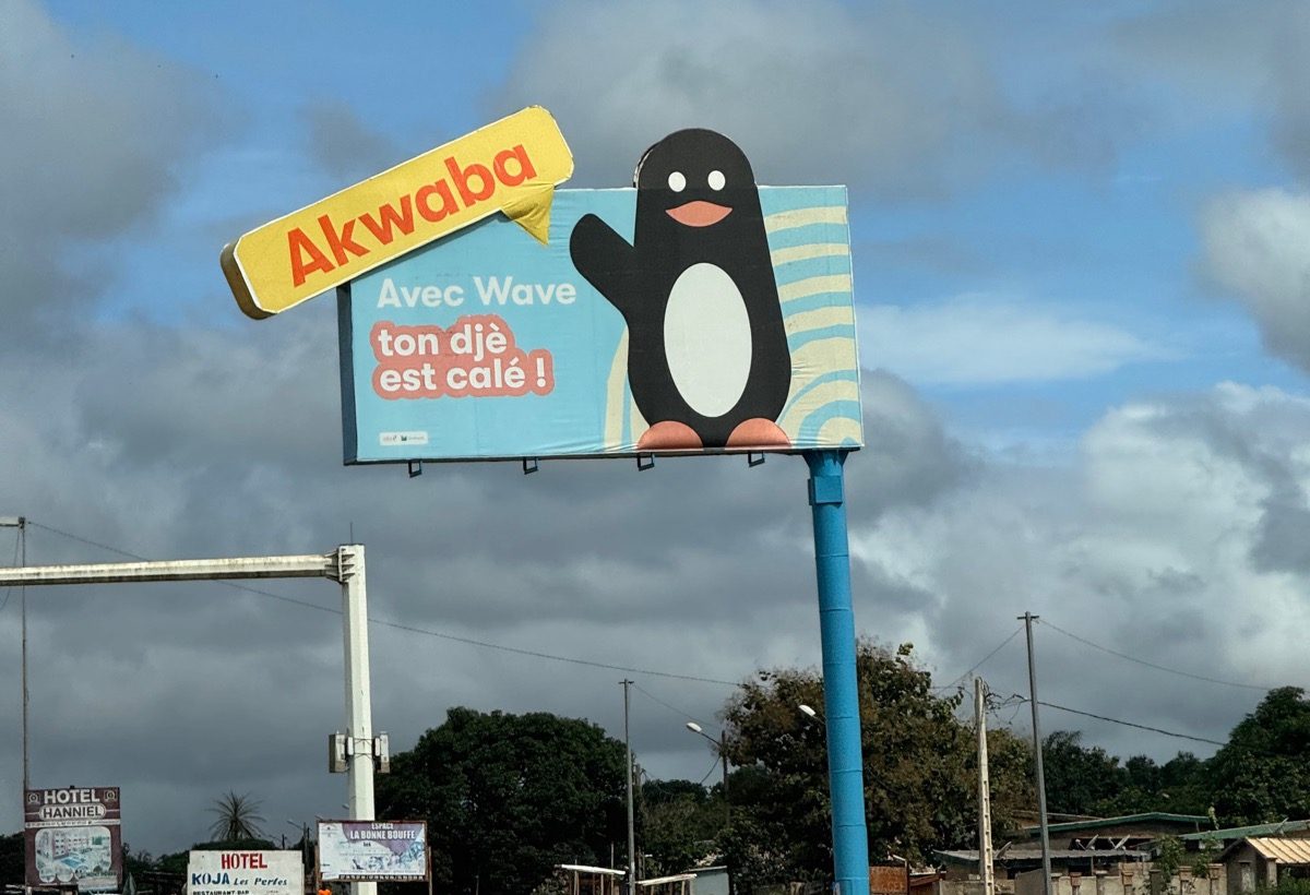 Roadside billboard in Côte d'Ivoire: a mobile money brand greets drivers with Akwaba and a Nouchi slogan